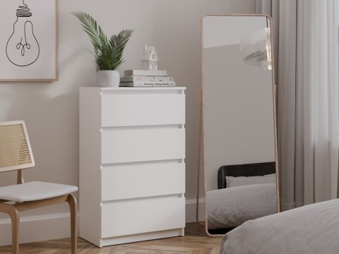 Stylowe, minimalistyczne wnętrze z białą komodą z szufladami KOM-930-BIEL-MAT ustawioną w półprofilu.
