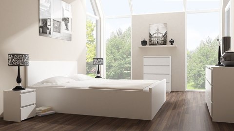 Stylowe wnętrze z komodą KOM-906-BIEL-MAT w aranżacji sypialni - widok boczny tuż obok łóżka.