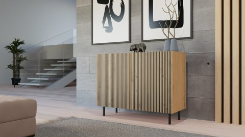 Wizualizacja przytulnego salonu z produktem: dwudrzwiowa komoda z lamelami dąb artisan KOM-922-ART-LAM.