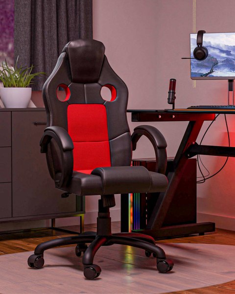 Fotel gamingowy FOT-407-CZER w aranżacji stanowiska e-sportowego – widok w półprofilu z podświetleniem LED w tle.