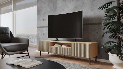 Stylowe wnętrze salonu z szafką pod telewizor dąb artisan RTV-507-ART-LAM w półprofilu, ze stojącym na niej telewizorem.